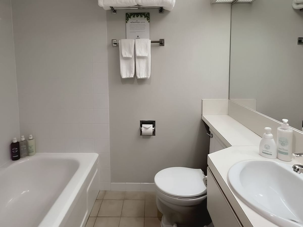 Bathroom with towels, toilet, mirror, bath and sink
