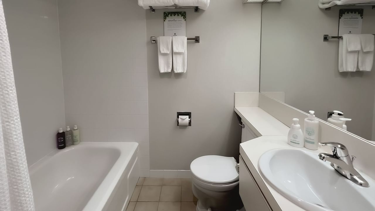 Bathroom with towels, toilet, mirror, bath and sink