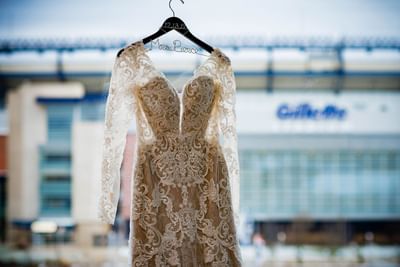 wedding dress on hanger with stadium in background