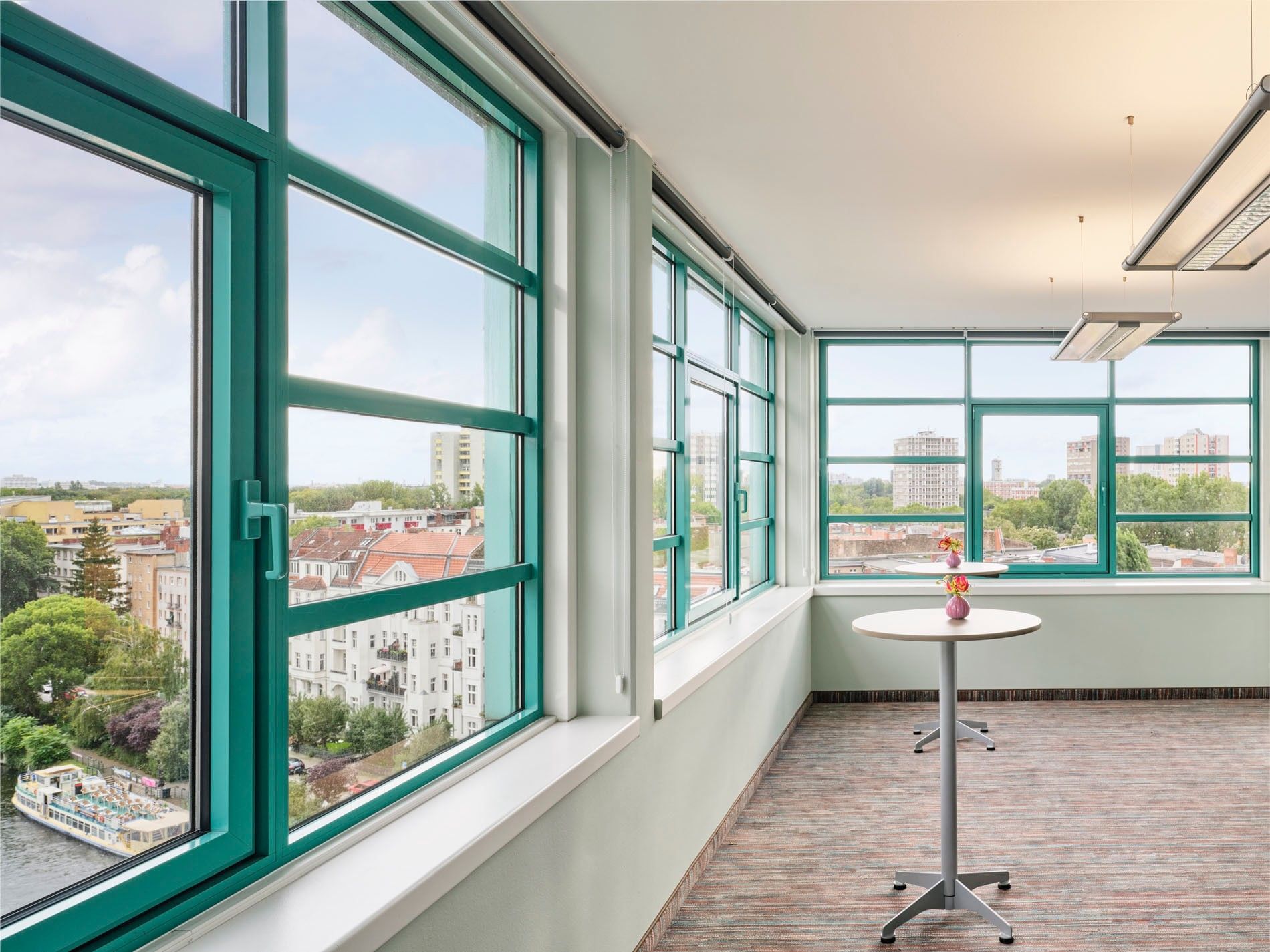 Panoramic city view through large green windows at Abion Spreebogen Waterside Hotel Berlin.