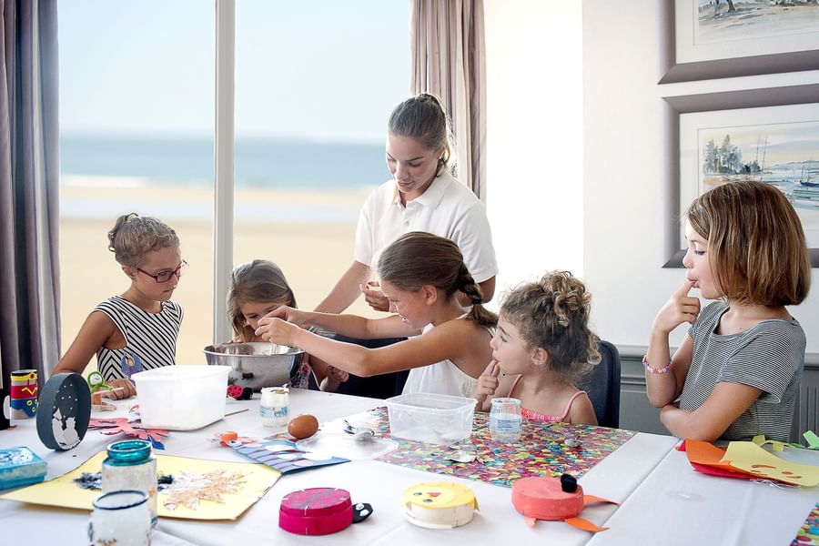 Group of kids enjoying a creative arts and crafts workshop at a bright table at Le Grand Hôtel des Thermes