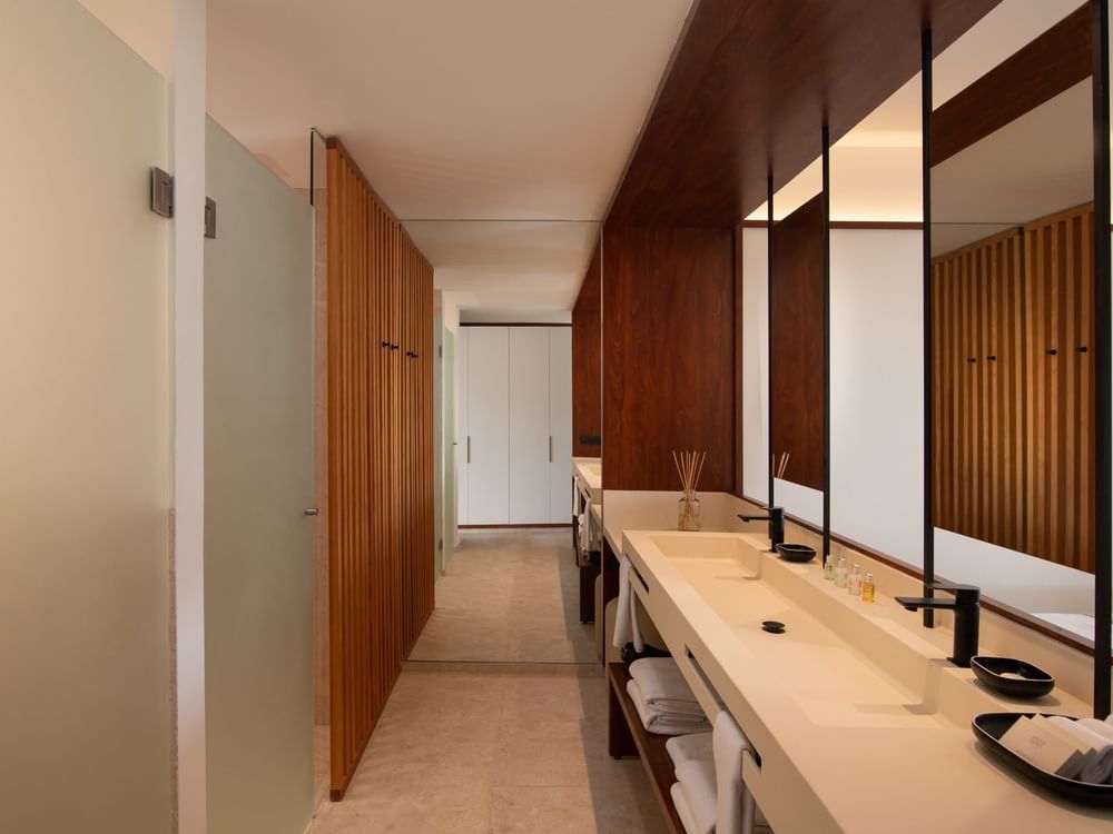 Modern bathroom with vanities, mirror and a hallway in Junior Suite Deluxe Pool View at Live Aqua Punta Cana