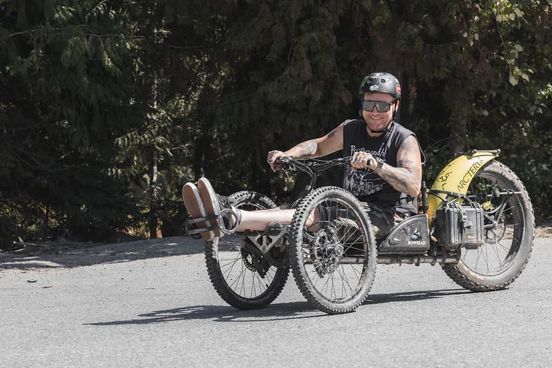 Man on a three wheel bicycle posing near Blackcomb Springs Suites