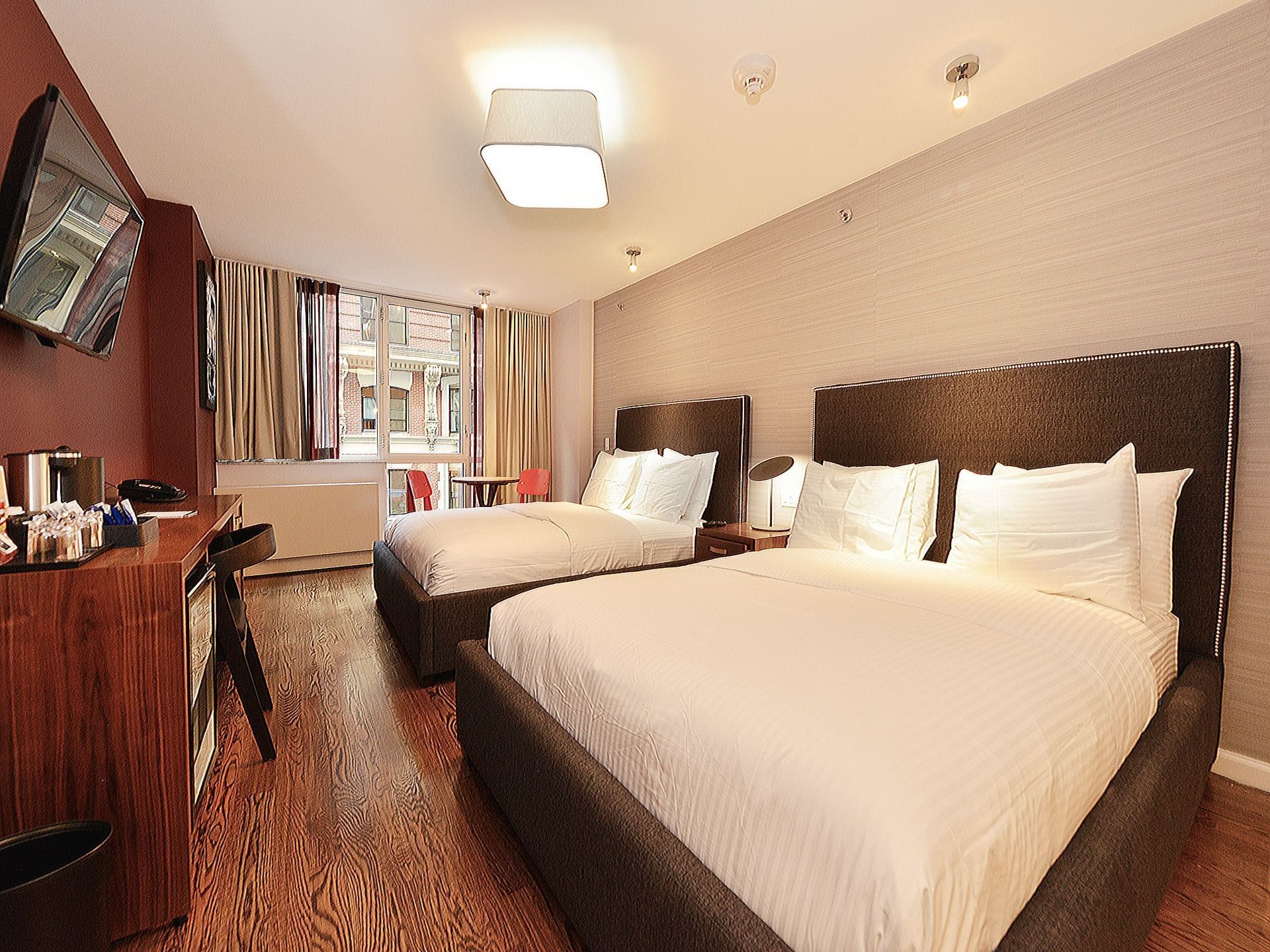 A hotel room with two double beds, a desk, and a window.