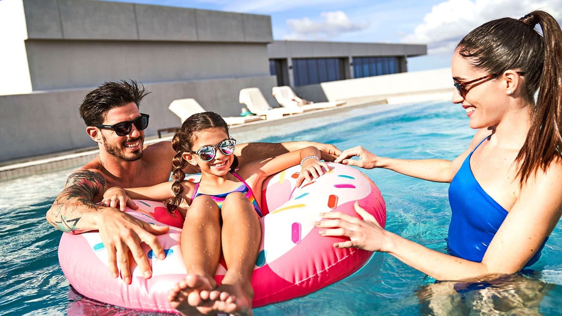 Family lounging in the outdoor pool at IOH Freestyle Hotels