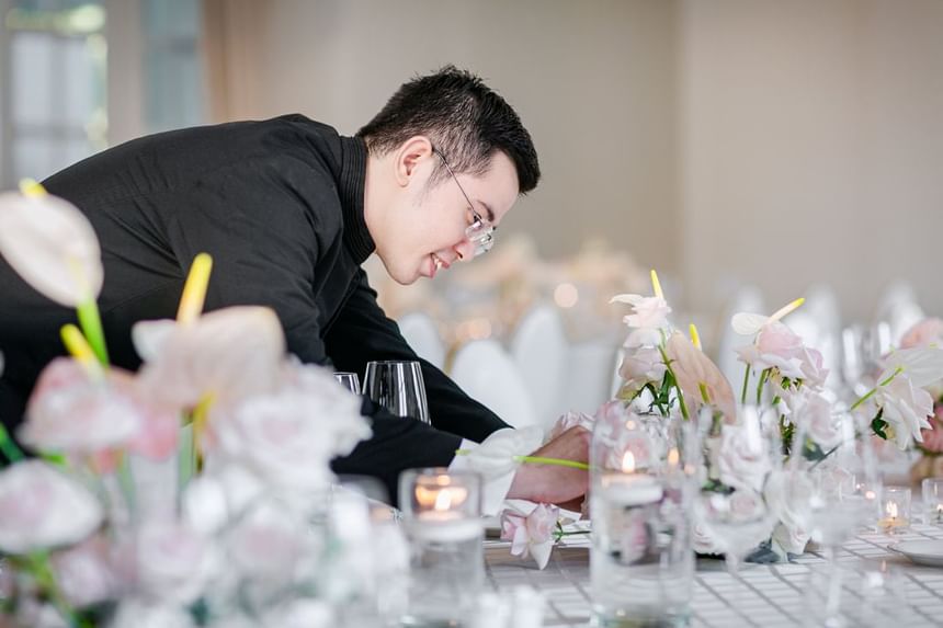 Staff arranging elegant pink flowers and candles on a dining table for an event at Park Hyatt Saigon