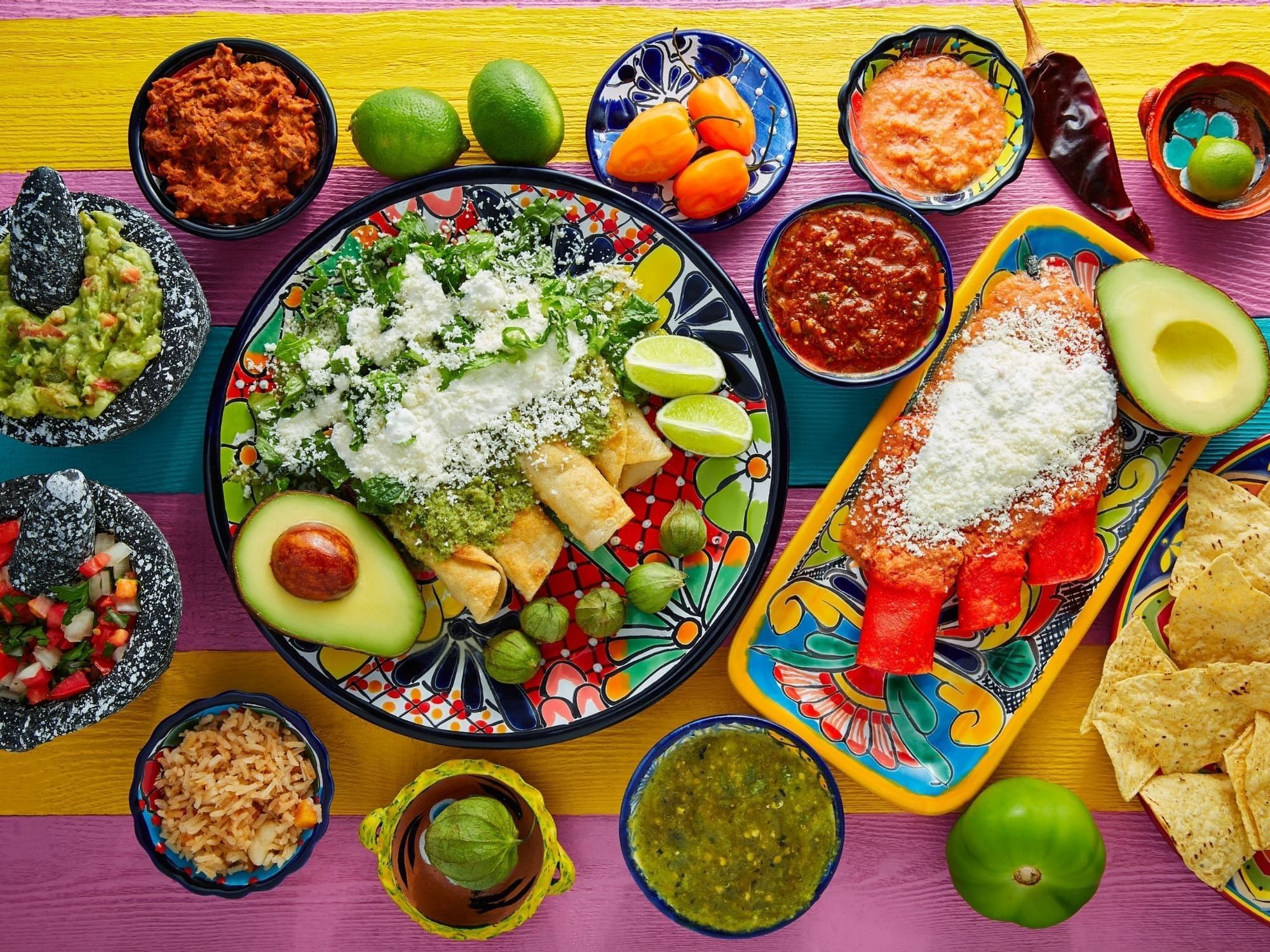 Colorful table with mexican food including enchildas and salsa