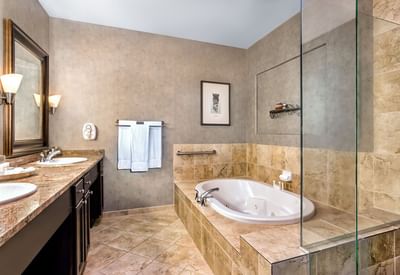 Modern multi-level Executive Suite bathroom at Hilton Santa Fe Buffalo Thunder featuring a bathtub, vanity, and shower areas