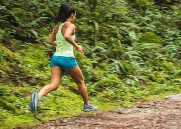 Close-up of a lady running on a trail by a forest near Blackcomb Springs Suites