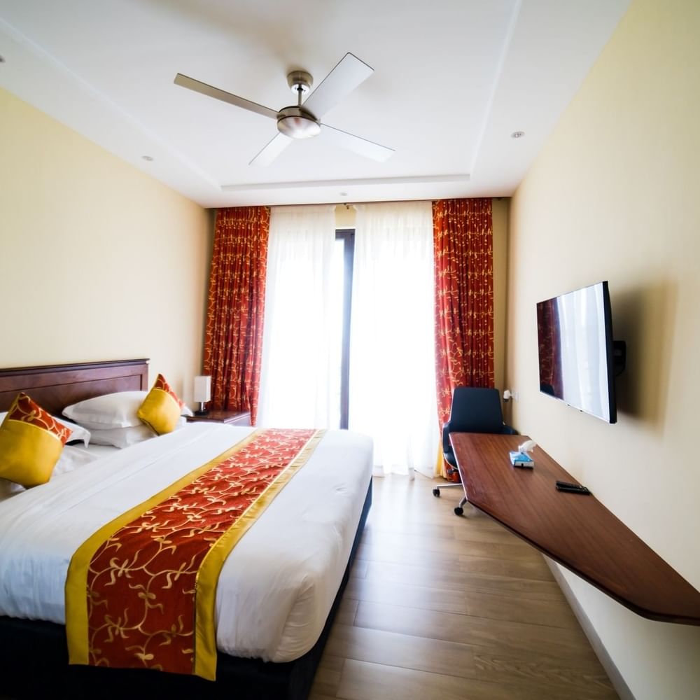 Bedroom with fan, TV, and balcony view at Lake Victoria Serena Golf Resort & Spa in Kampala.
