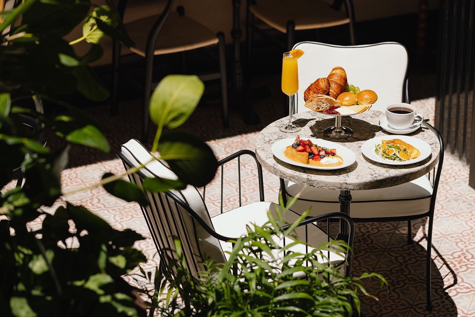 A table set for breakfast or brunch with food and drinks in an outdoor seating area.
