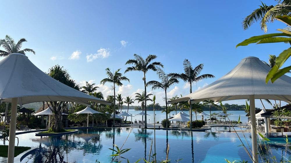 Large pool with beach umbrellas and palm trees at Warwick Le Lagon Efate.