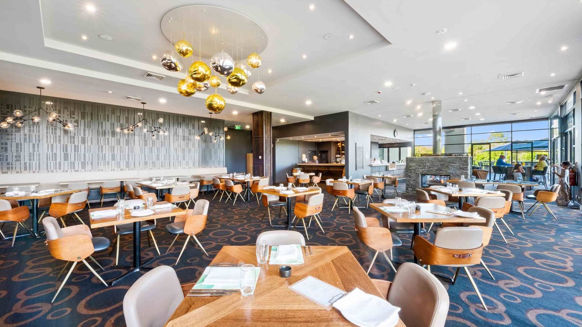 Karinyas Restaurant interior with dining chairs and tables, decorative gold pendant lights at Mercure Kooindah Waters