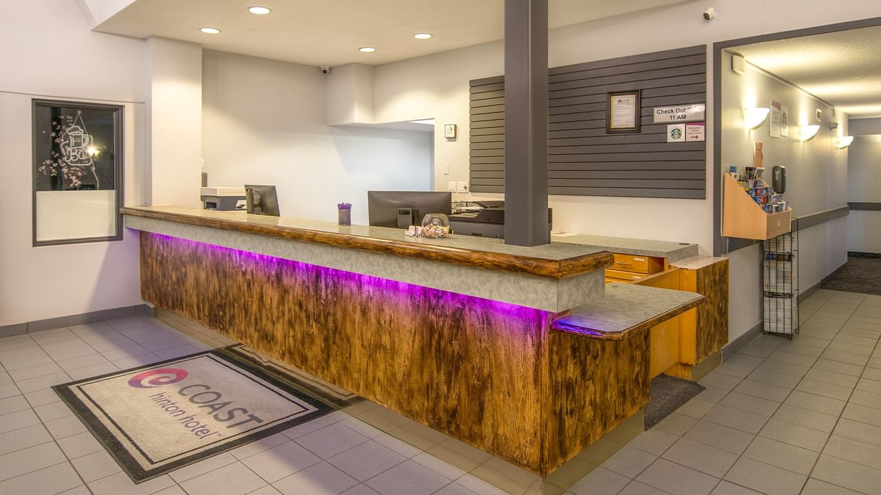 A hotel reception desk with wooden design, monitors, and a