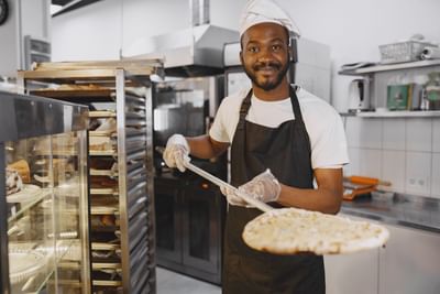 A baker tossing pizza in the oven at Azalai Hotel Dakar