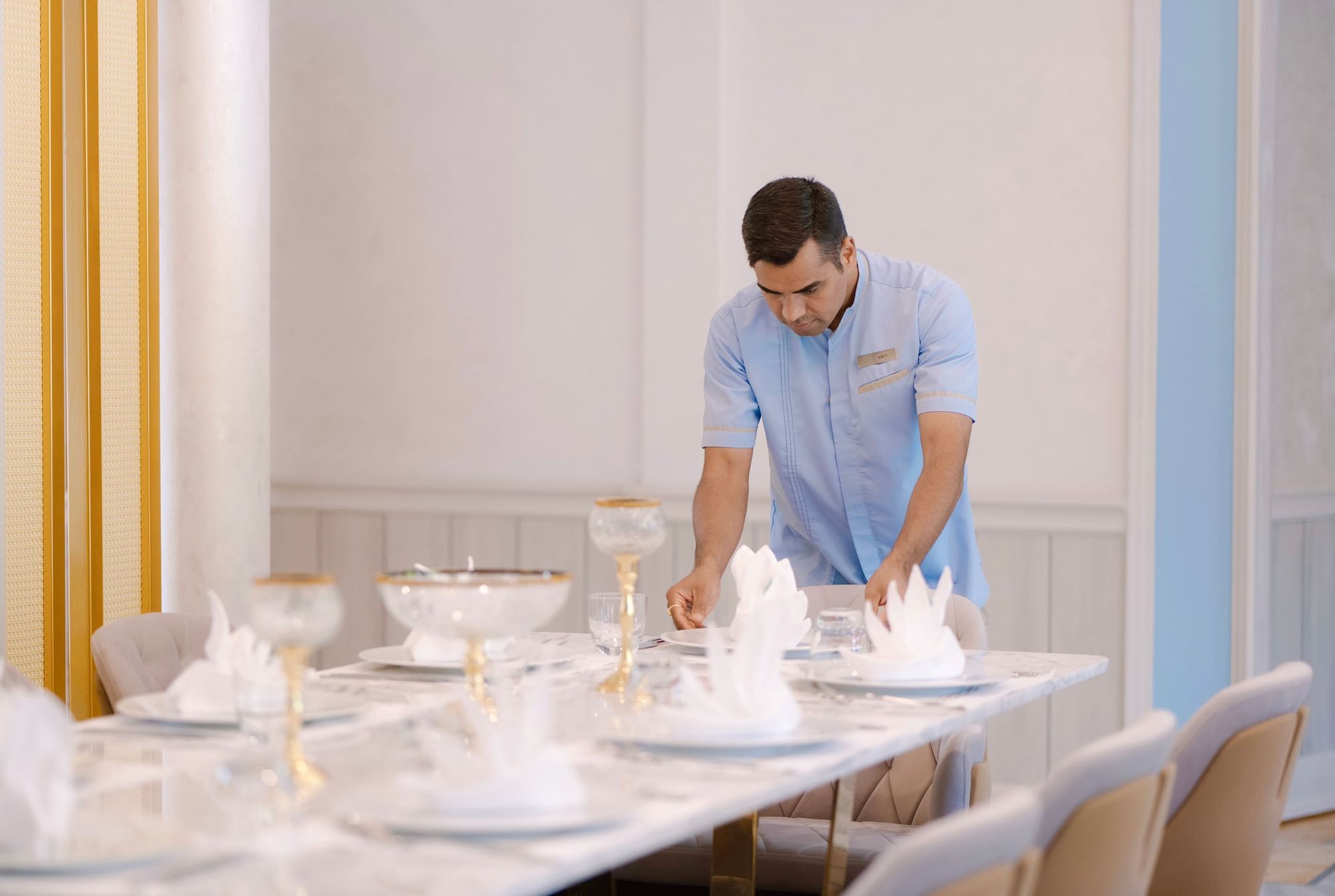 A butler arranging a dining table at The Signature Collection