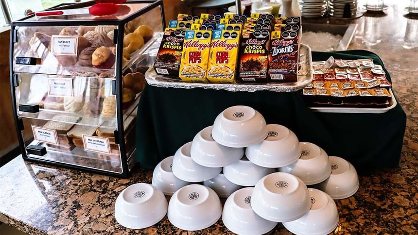 Bufé de desayuno con pasteles, cajas de cereales y cuencos blancos sobre granito en La Pérgola de Araiza Palmira 