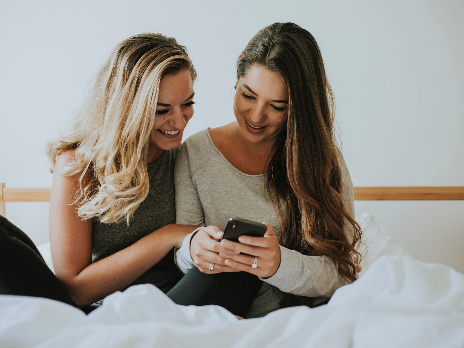 Two girls using a phone on the bed at Nesuto Stadium Hotel and Apartments