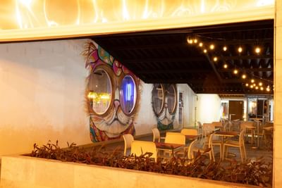 Outdoor seating area with string lights and colorful mural at MARINN Tropical Vibes Hotel