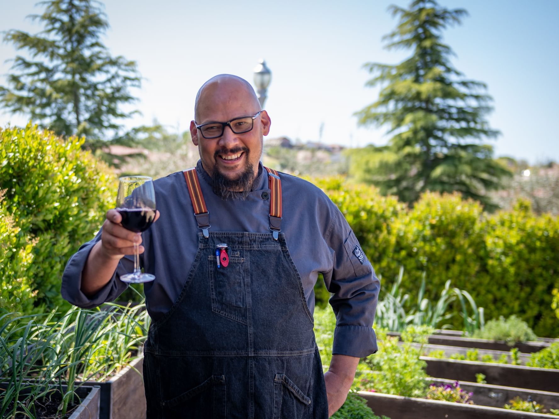 Executive Chef, Jeremy Fike, holding glass of wine in front of garden