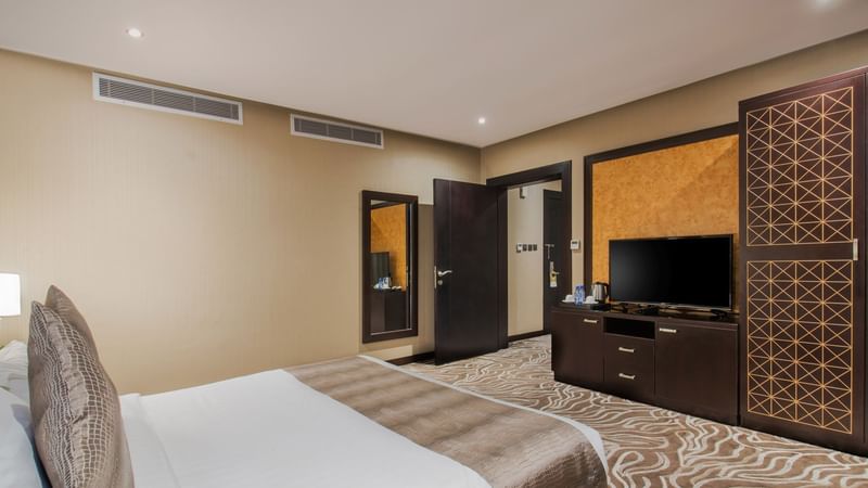 Two beds with open doors leading to the living area in Junior Suite at Warwick Al Khobar