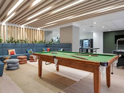 Modern recreation room with pool table, air hockey, lounge seating, and wooden slatted ceiling at UniLodge Auckland Central