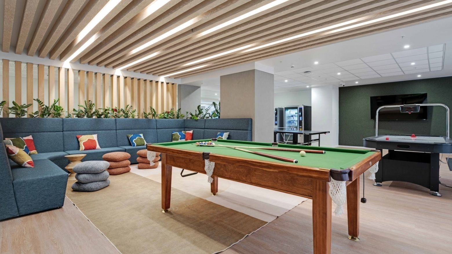 Modern recreation room with pool table, air hockey, lounge seating, and wooden slatted ceiling at UniLodge Auckland Central