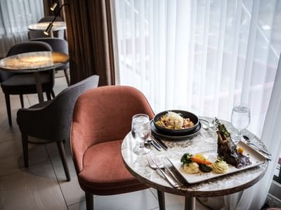 A stylish dining setup with a peach armchair and gourmet dishes served at Matrix Hotel