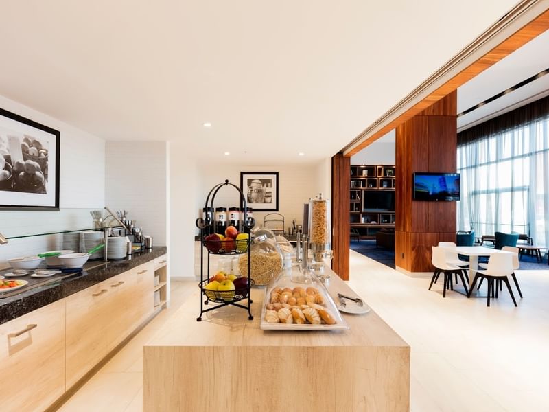 Breakfast Room at Hampton Inn by Hilton Cancun Cumbres with fruit, pastries, cereal, and a view into the lobby lounge