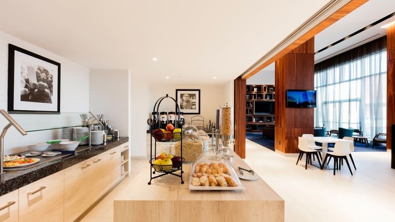 Buffet counter at Fiesta Inn Express Cancún Cumbres with fruit and pastries on a wooden island, Cancun hotel breakfast