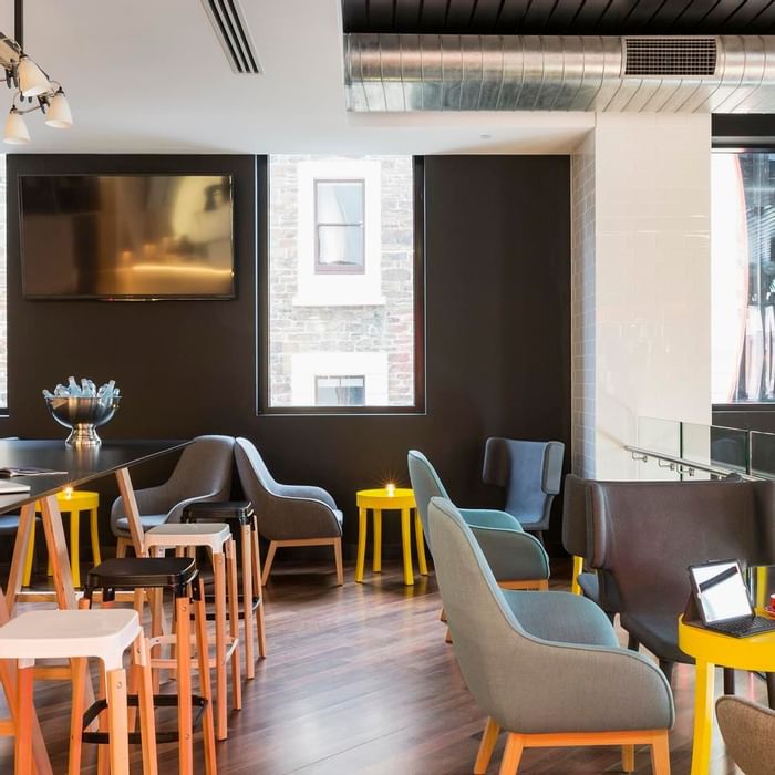 Level One Bar with modern seating, yellow tables, and a large communal desk at Ibis Adelaide