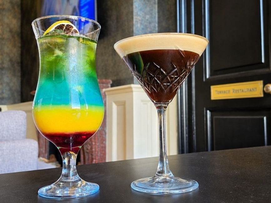 Two colourful cocktails on a dark table at Easthampstead Park Bar, Easthampstead Park Hotel, Bracknell