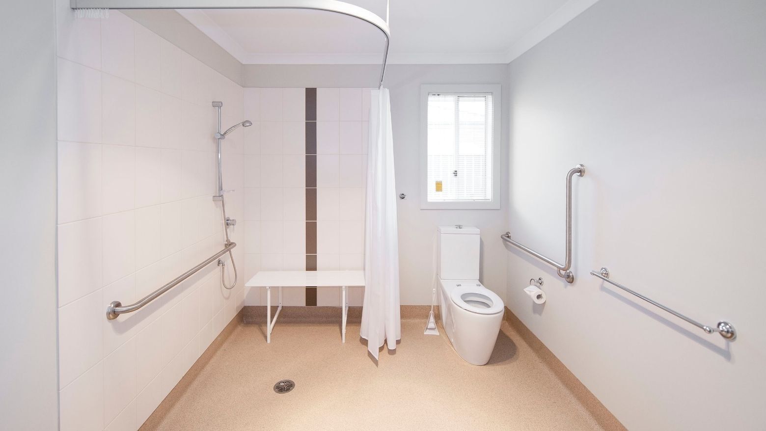 Clean bathroom with accessible toilet, shower, and support bars at La Trobe University Regional Housing – Shepparton.