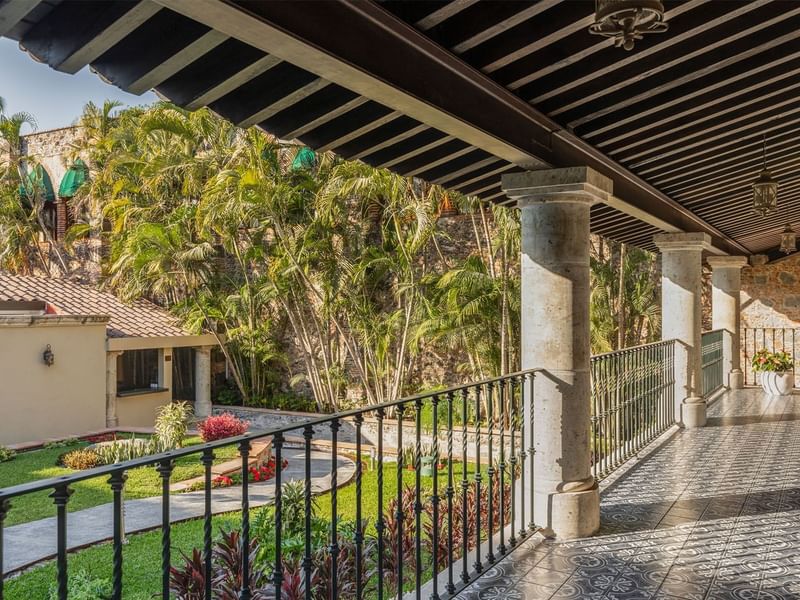 Spacious outdoor corridor at Fiesta Americana, featuring ornate tiling, sturdy columns, and a view of lush palm trees