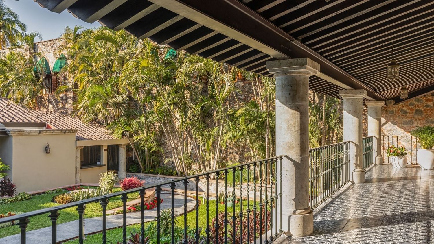 Spacious outdoor corridor at Fiesta Americana, featuring ornate tiling, sturdy columns, and a view of lush palm trees