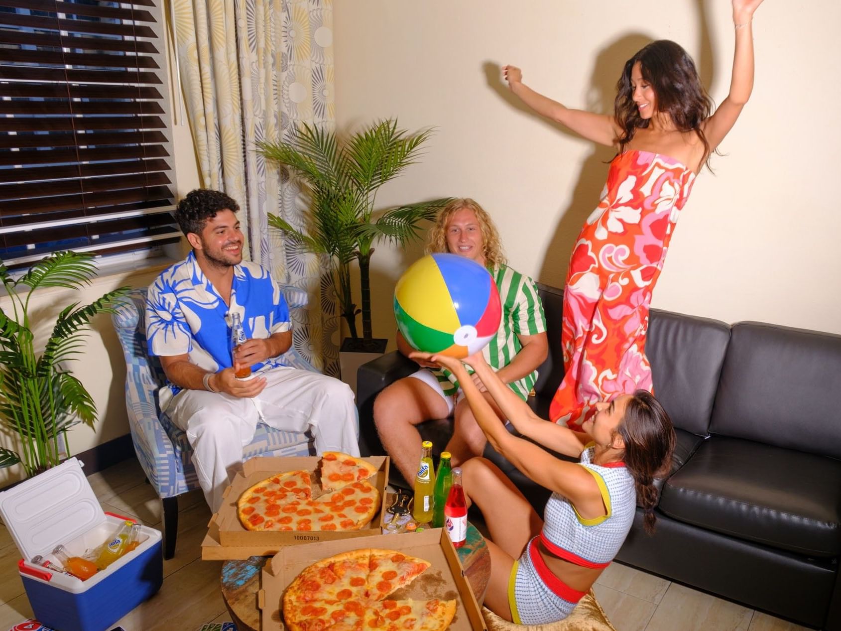 Guests enjoy a lively pizza party and beach ball fun in the spacious apartment living room at Tradewinds Apartment Hotel