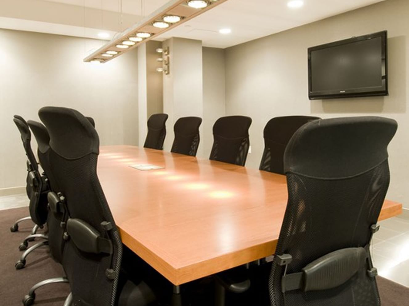 Modern meeting room at Soho 54 Hotel in NYC, featuring a large table, ergonomic chairs, and TV