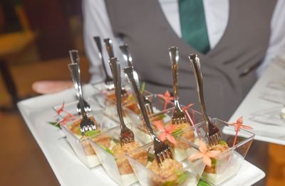 A chef serving desserts on a tray in a restaurant at Courtleigh Hotel & Suites