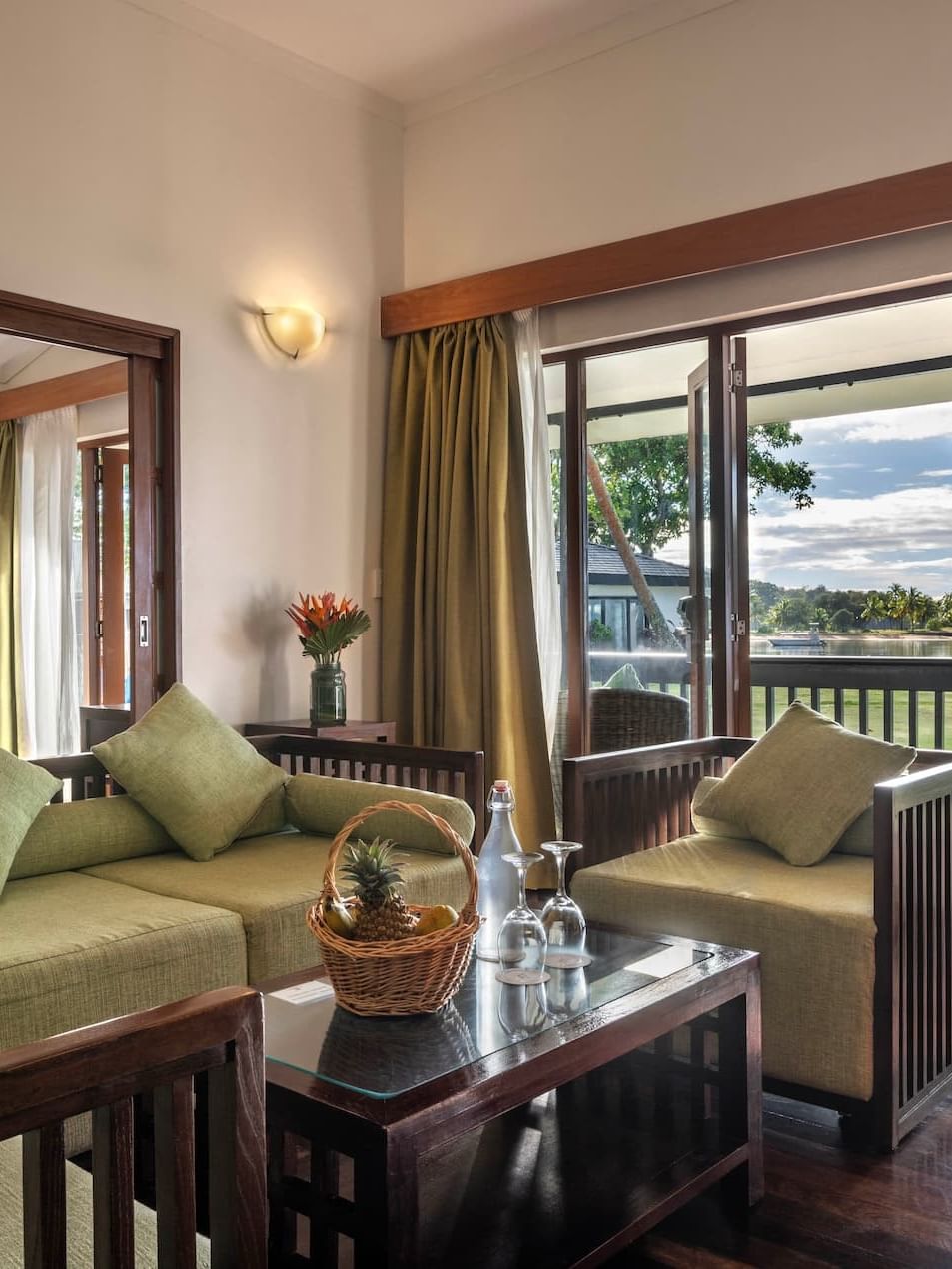 Green sofa by a coffee table under a wall sconce near a balcony in One-Bedroom Villa at The Naviti Resort - Fiji