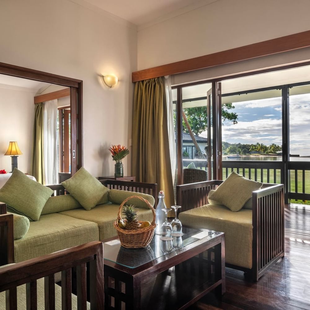Green sofa by a coffee table under a wall sconce near a balcony in One-Bedroom Villa at The Naviti Resort - Fiji