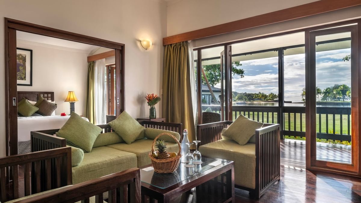 Green sofa by a coffee table under a wall sconce near a balcony in One-Bedroom Villa at The Naviti Resort - Fiji