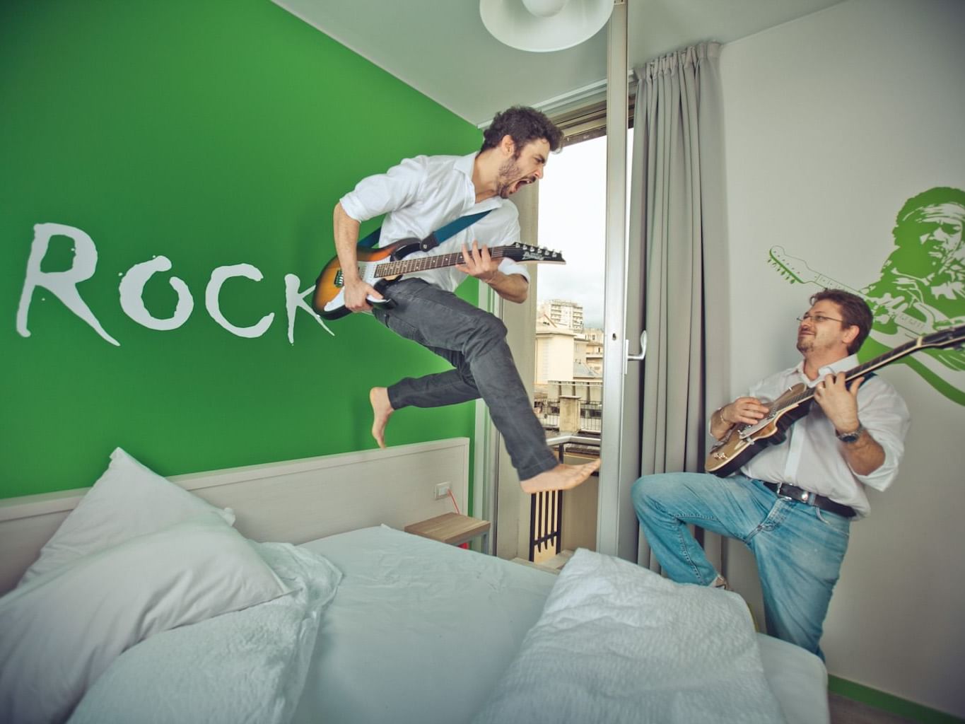 2 men playing guitar inside the Rock room at Hotel Nologo