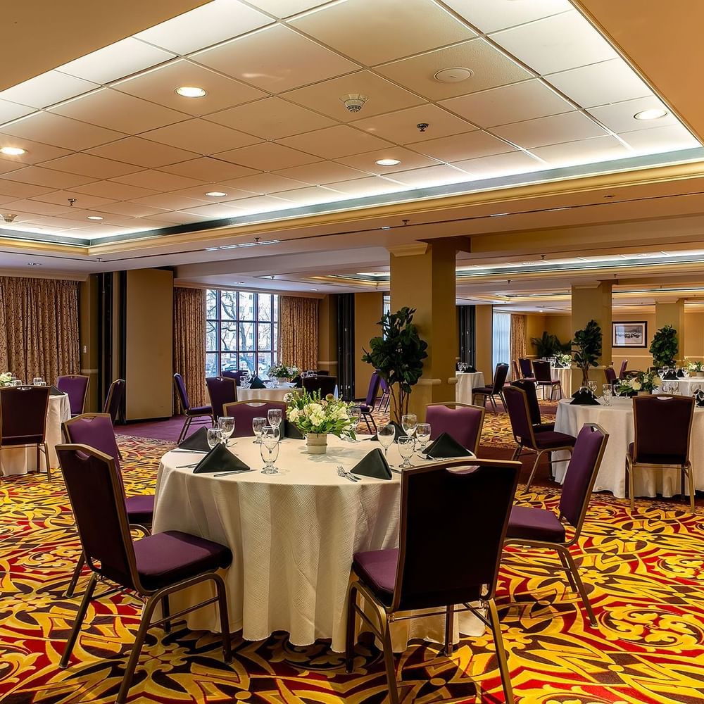 Capitol Ballroom at Warwick Denver with purple chairs by round tables under a bright tray ceiling