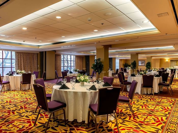 Capitol Ballroom at Warwick Denver with purple chairs by round tables under a bright tray ceiling