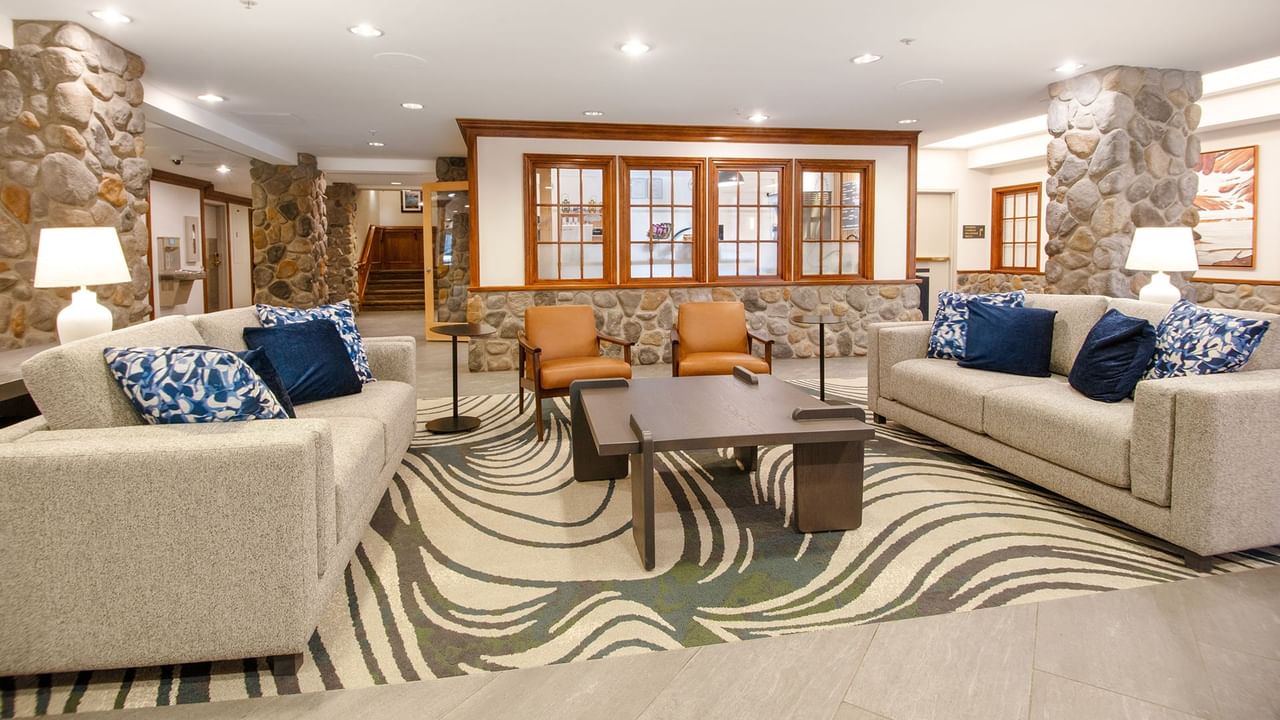 Lobby with couches, a coffee table, with stone walls and a staircase.