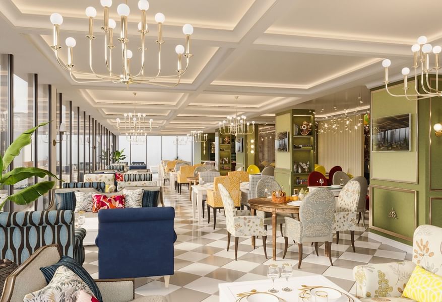 Patterned dining chairs by round wooden tables under gold chandeliers in The Tower View at Cantonal Hotel by Warwick Riyadh