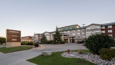 Exterior view of Sandman Hotel & Suites Winnipeg Airport with signage and parking