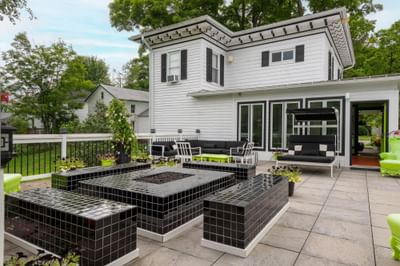 Modern outdoor patio featuring black and white furniture, a fire pit and lush greenery surrounding The Roxbury