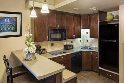 Modern kitchen with dark wood cabinets, tile backsplash, breakfast bar, and black appliances at London Bridge Resort
