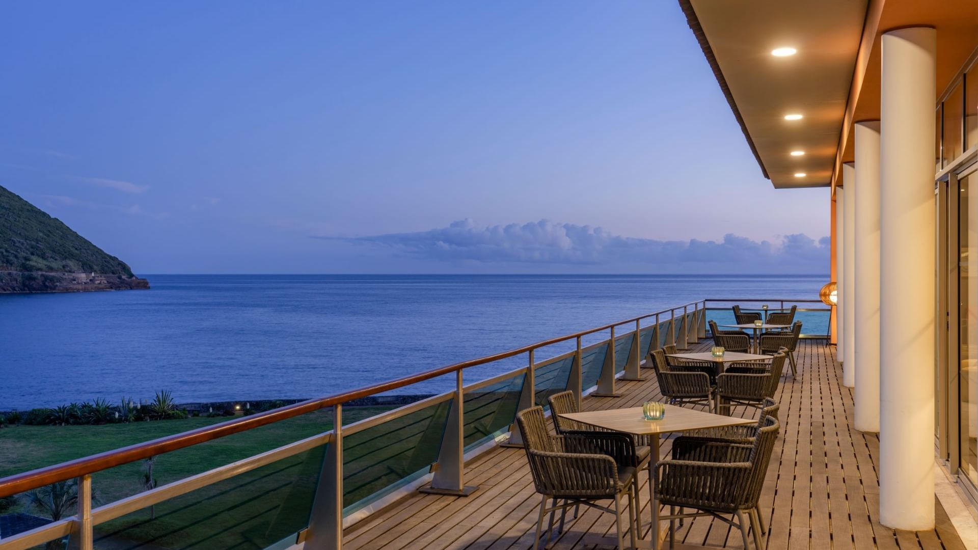 Illuminated outdoor dining area with a distant sea view in Fanal Bar at Terceira Mar Hotel